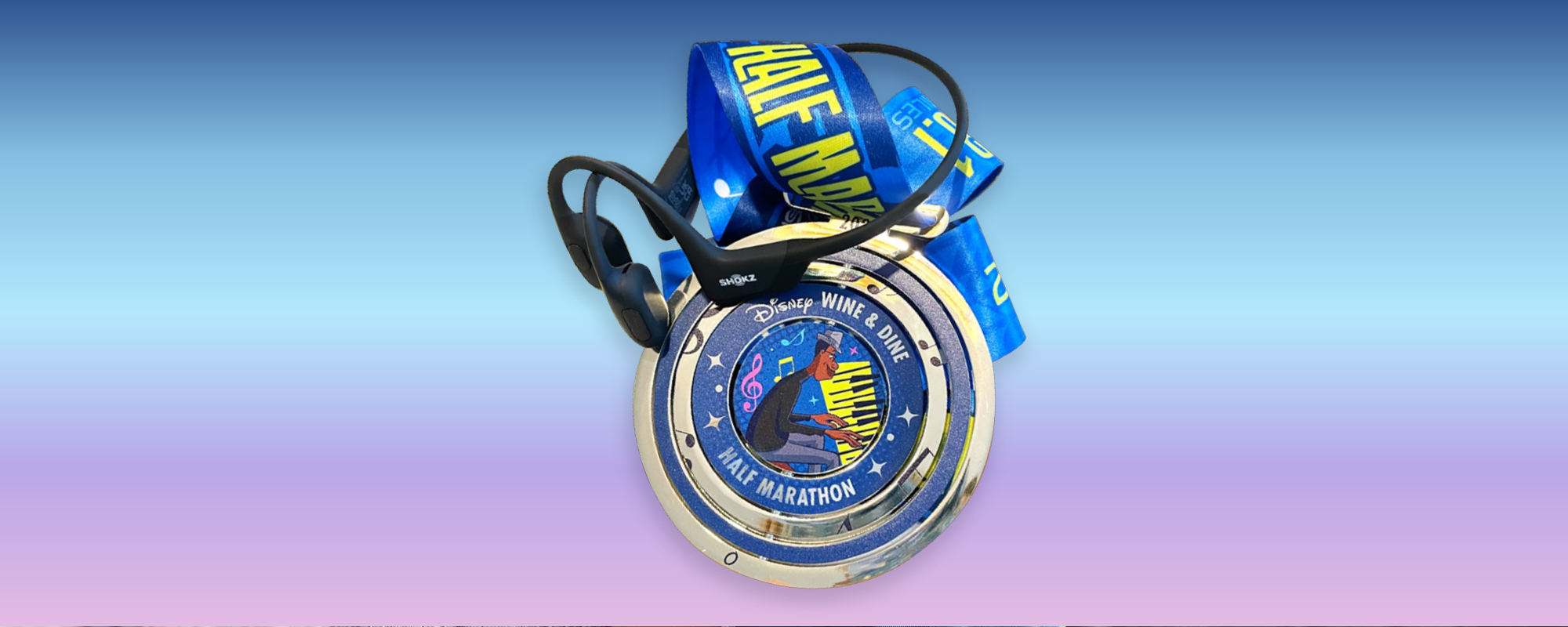 Close up image of the Wine and Dine Half Marathon medal and black Shokz OpenRun Pro headphones