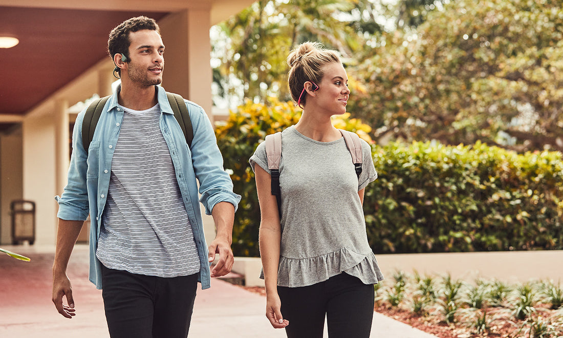 Man and woman walking in AfterShokz headphones.