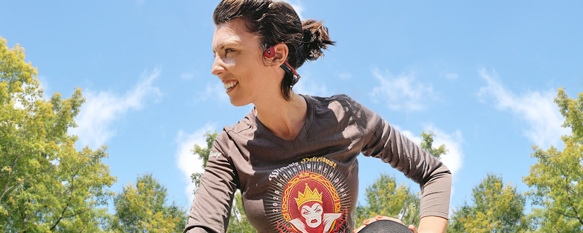 Woman in runDisney shirt wearing AfterShokz Air headphones