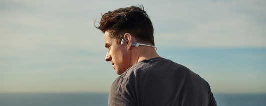 Man running outdoors while wearing AfterShokx Aeropex wireless headphones