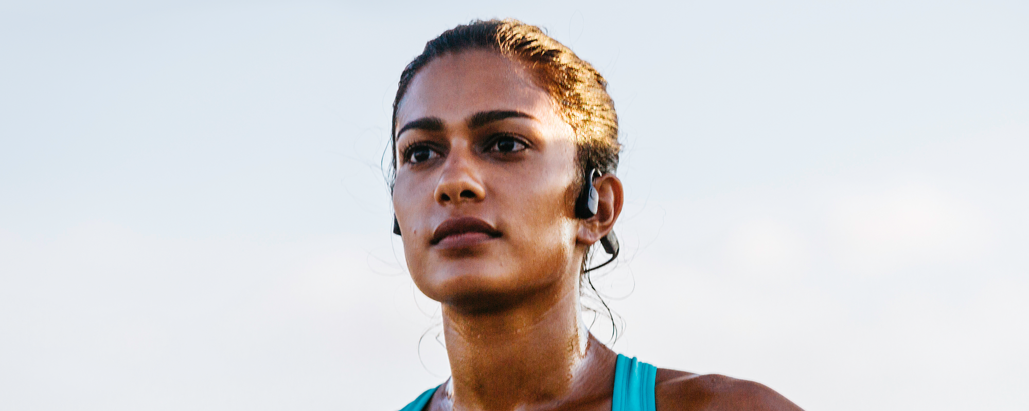 Close-up image running outdoors while wearing Shokz OpenRun sports headphones
