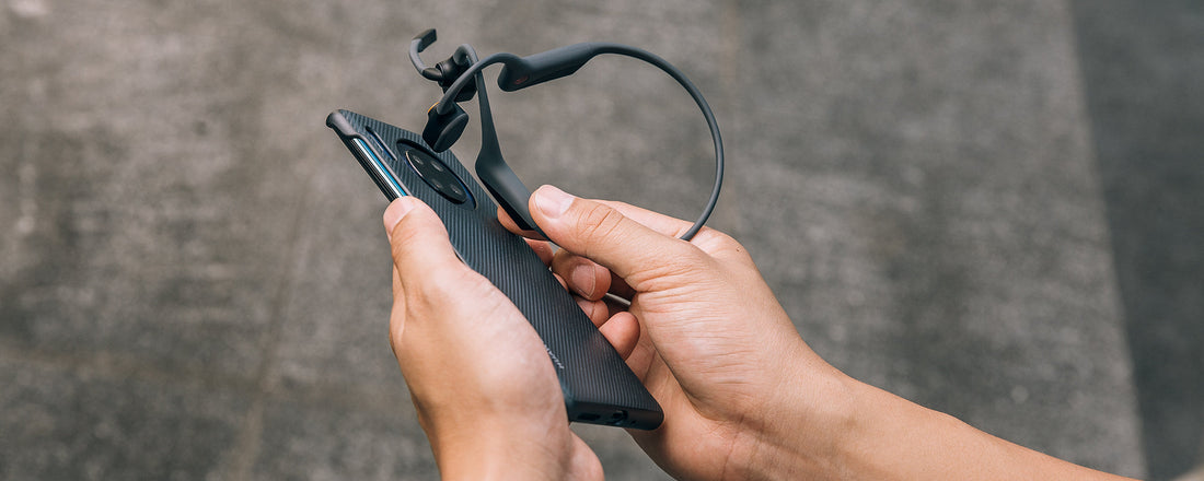 Person using NFC Pairing to sync AfterShokz OpenComm headset to device