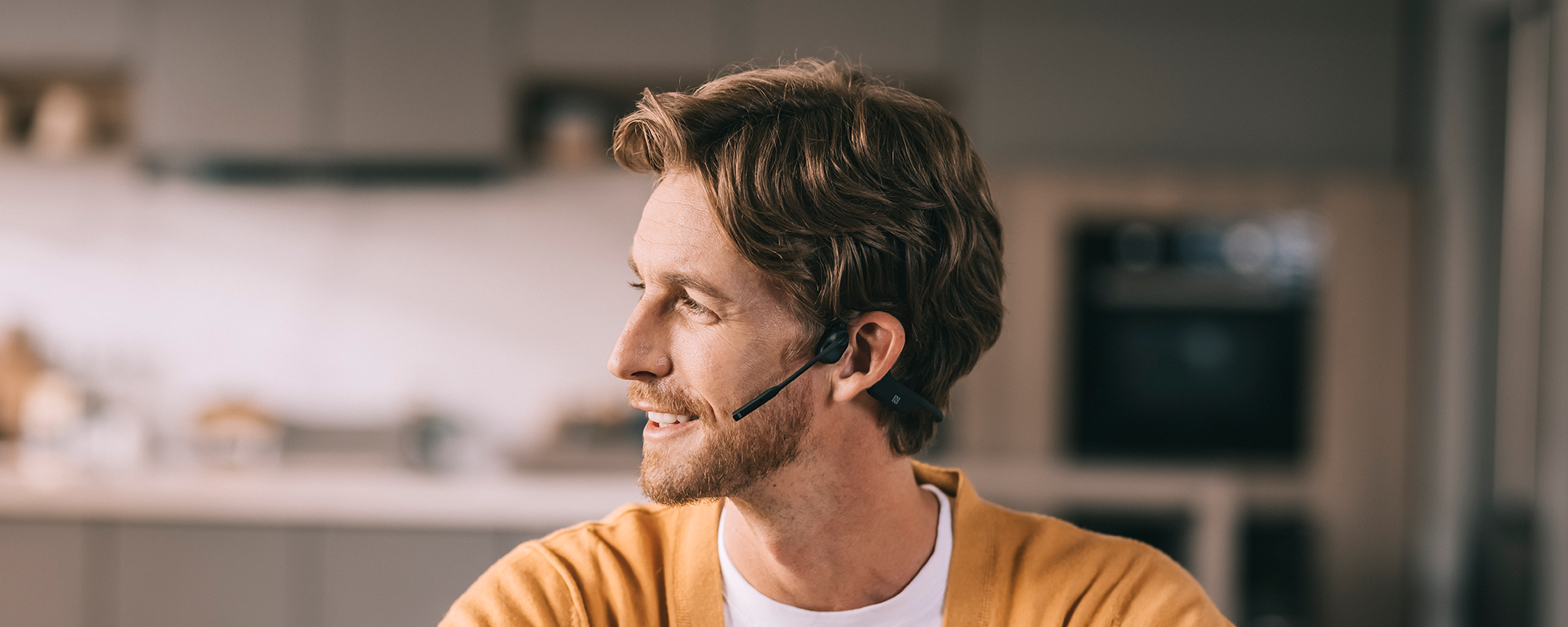Image of a man working from home and wearing Shokz OpenComm UC wireless headset