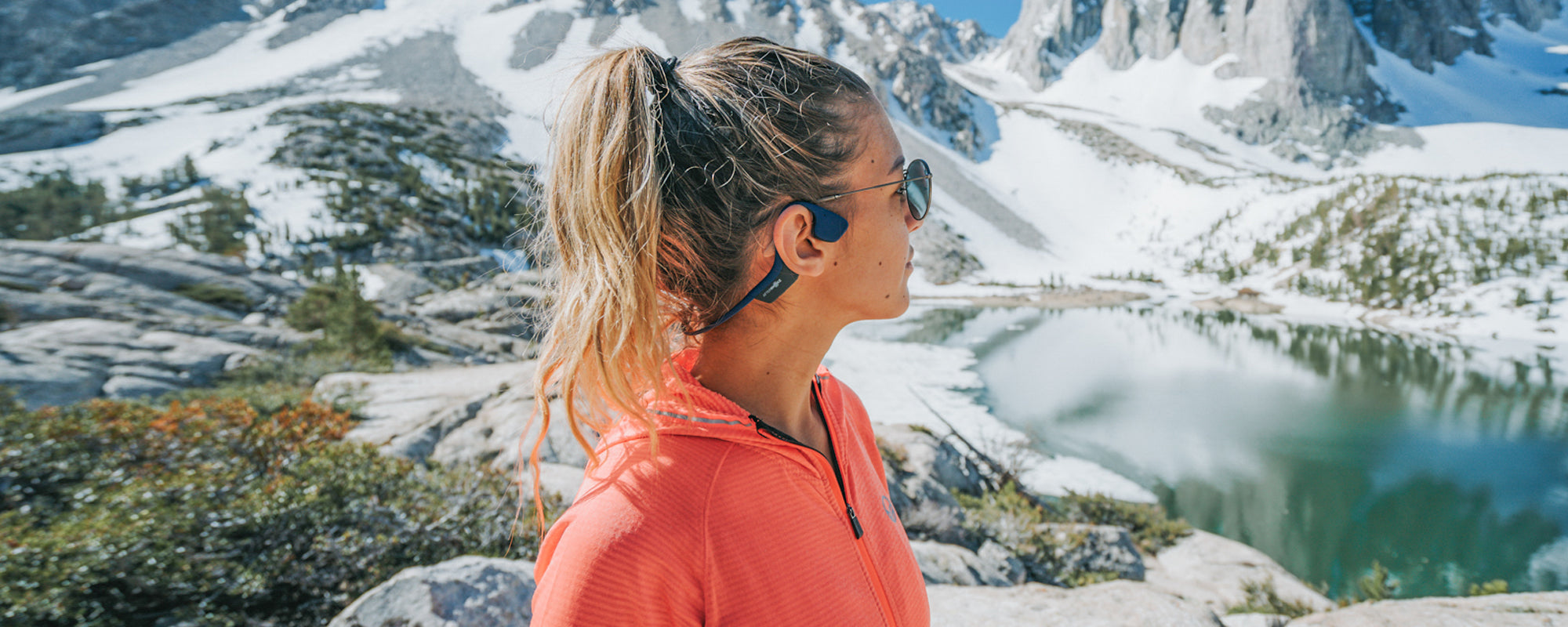 Woman hiking in the mountains while wearing AfterShokz Aeropex wireless headphones