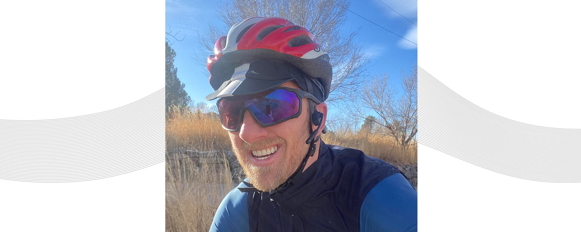 Dr. Justin Ross riding his bike while wearing a helmet and AfterShokz Aeropex headphones