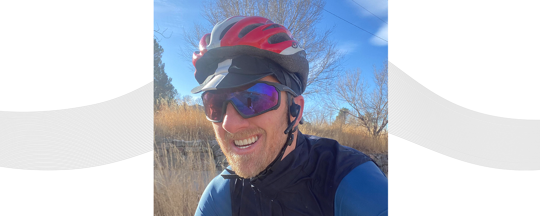 Dr. Justin Ross riding his bike while wearing a helmet and AfterShokz Aeropex headphones