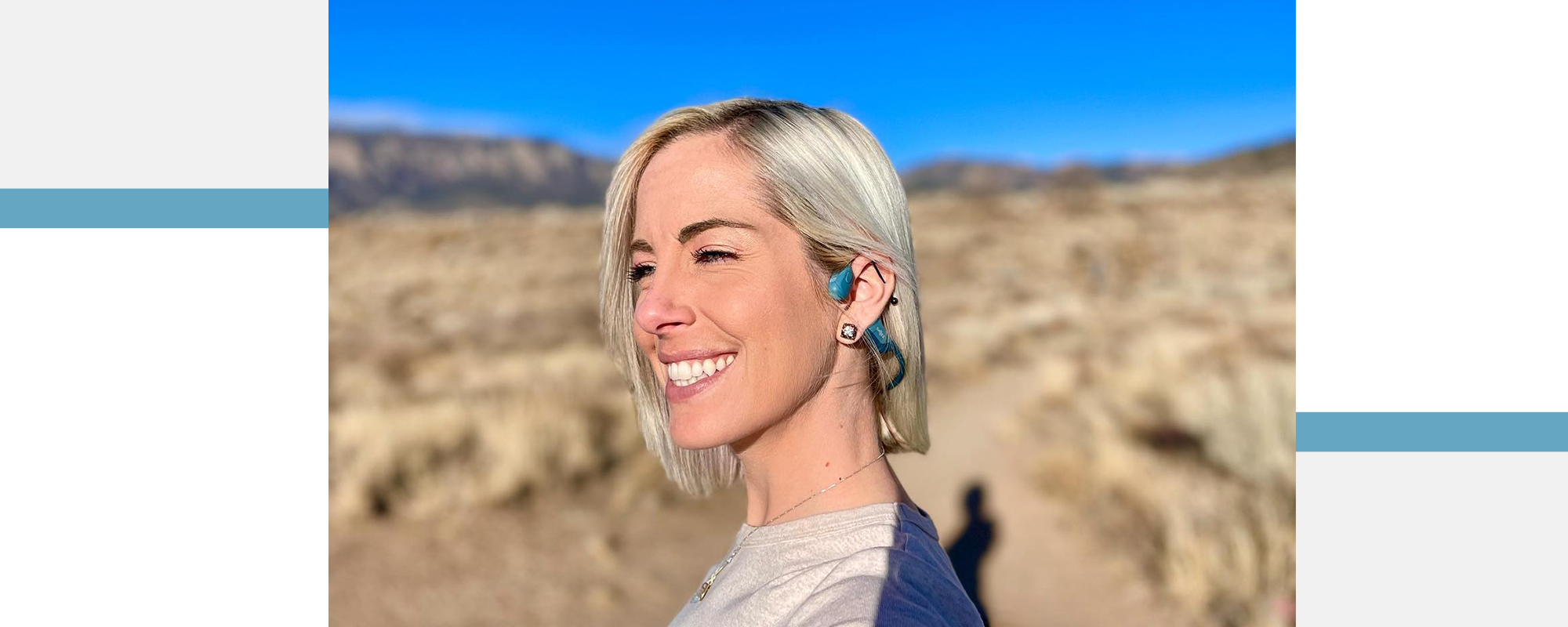 Woman outside smiling and wearing blue Shokz OpenRun Pro wireless sport headphones 