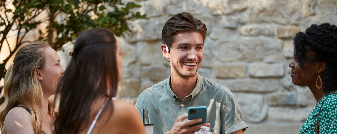 Group of friends talking and wearing AfterShokz wireless headphones
