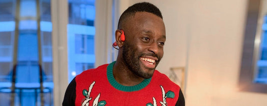 Man wearing Christmas sweater and AfterShokz Aeropex wireless headphones
