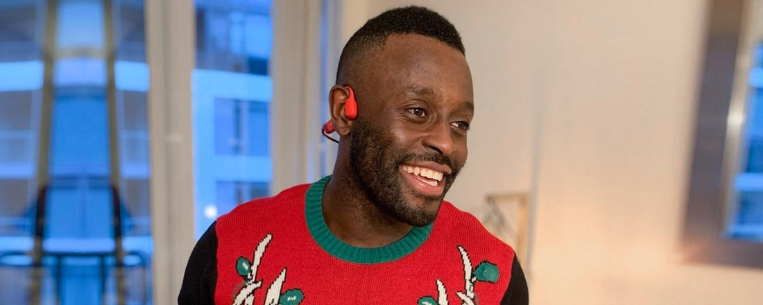 Man wearing Christmas sweater and AfterShokz Aeropex wireless headphones