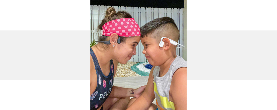 Mother wearing OpenRun wireless headphones with her son wearing OpenMove wireless headphones