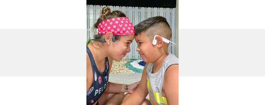 Mother wearing OpenRun wireless headphones with her son wearing OpenMove wireless headphones