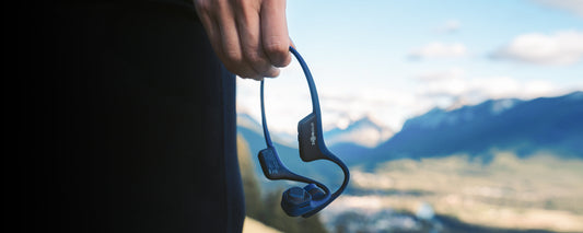 Person holding a pair of AfterShokz Air wireless headphones